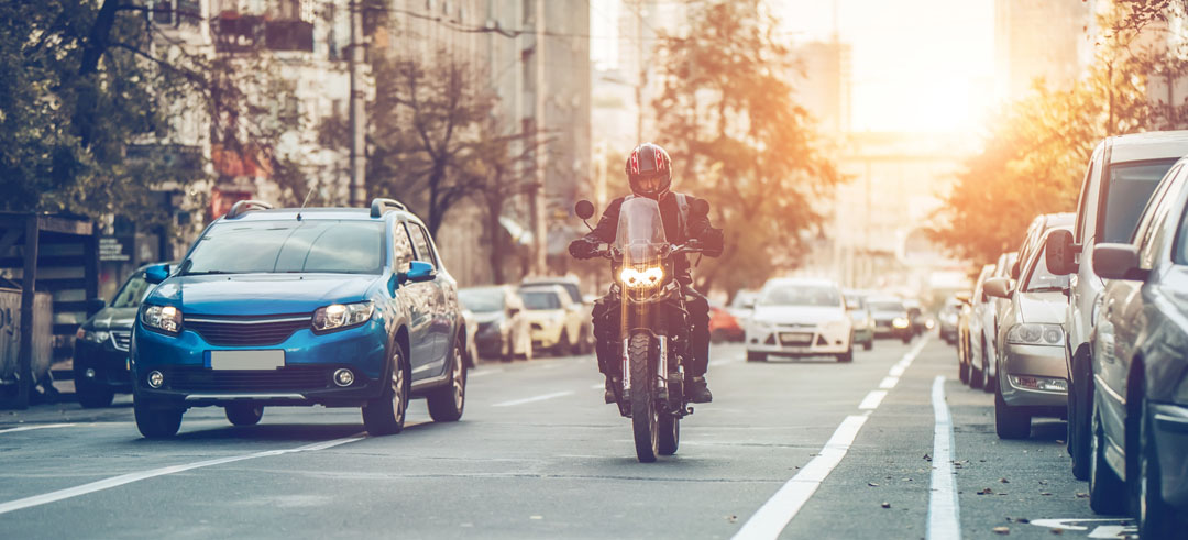 Una moto y varios coches circulando por una carretera mientras otros están apartados