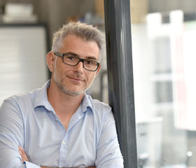 Hombre apoyado en una pared de cristal