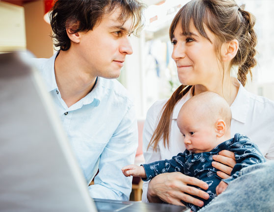 Pareja mirándose fijamente a los ojos mientras la mujer sostiene a un bebé en brazos