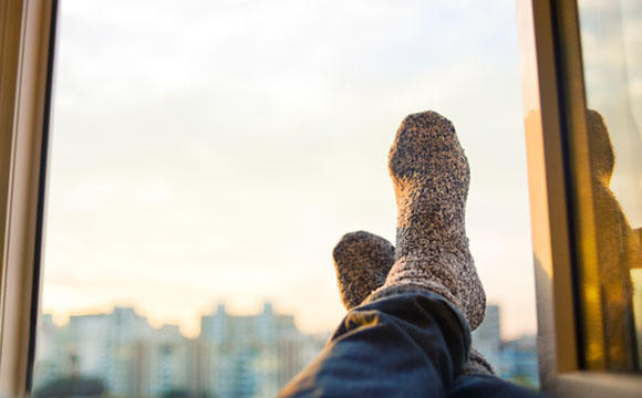 pies apoyados, en una ventana con vistas a una ciudad