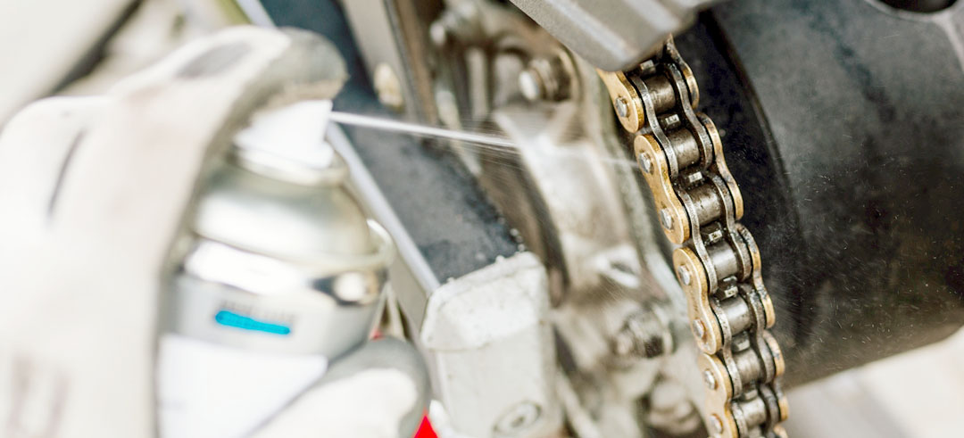 Persona engrasando la cadena de una motocicleta